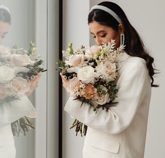 A beautiful woman in a white wedding suit with flowers smelling her bouquet in a chic sparkling headband. We dive into wedding trends for the future.