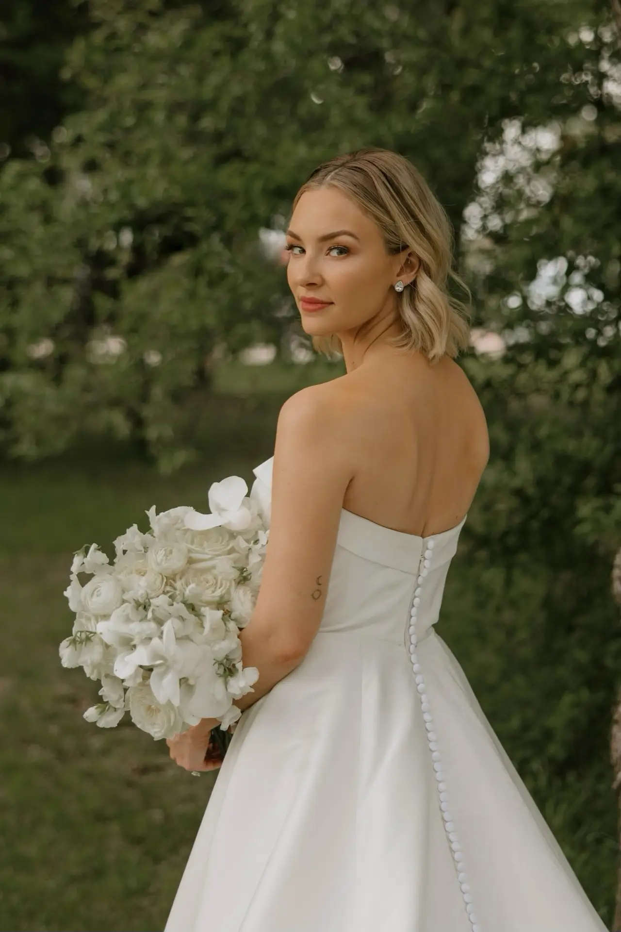 Bride looking back over her shoulder in a custom Margo West gown, Dallas TX