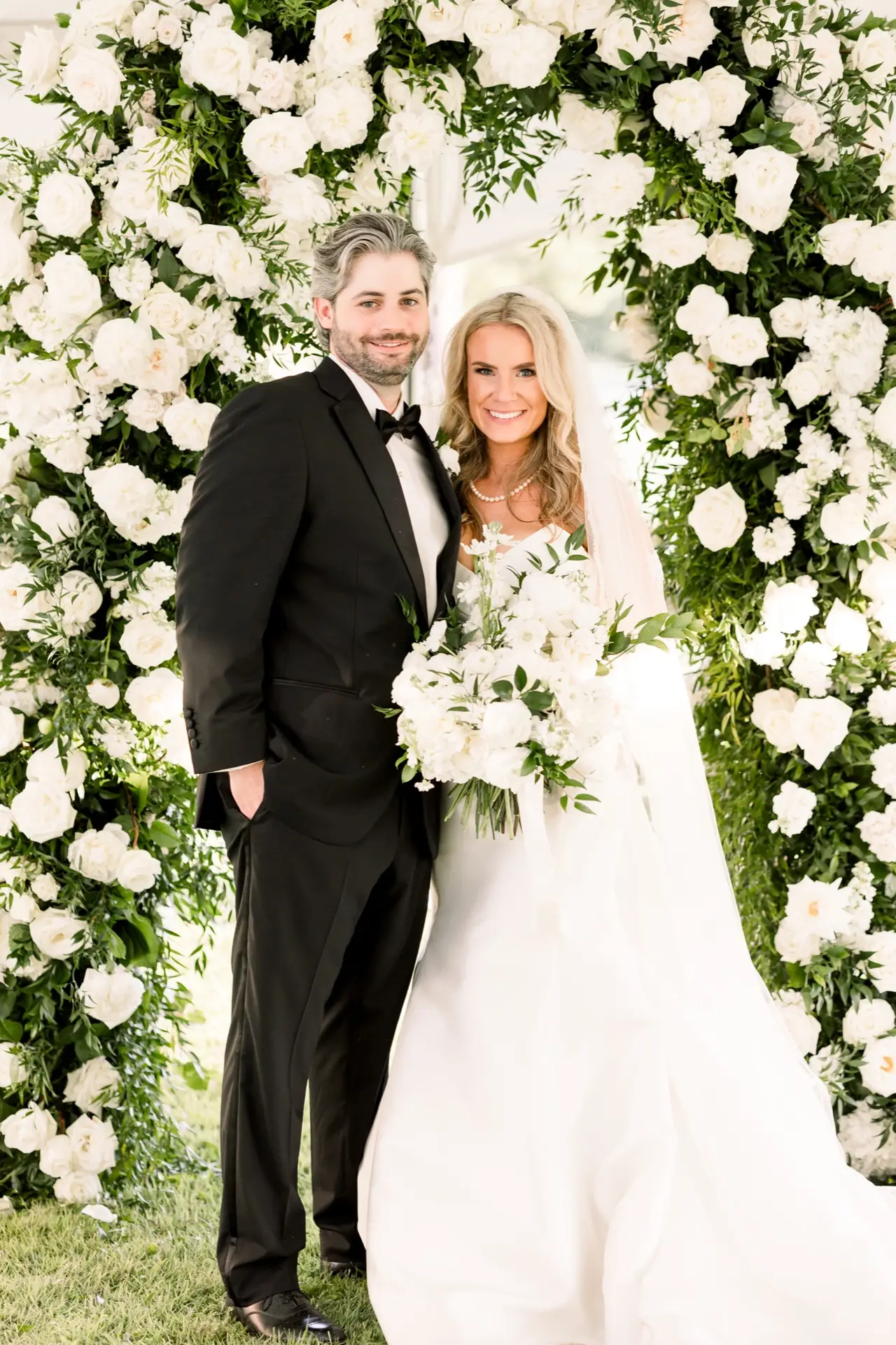 Lily Smith and groom under floral arch, custom Margo West wedding gown, Dallas TX